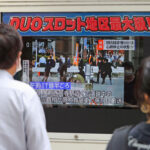 People watch TV news reporting Japan’s former Prime Minister Shinzo Abe was shot, in Tokyo, Friday, July 8, 2022. Kyodo News