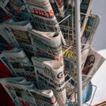 Close-up of a newspaper stand with various publications on a city sidewalk.